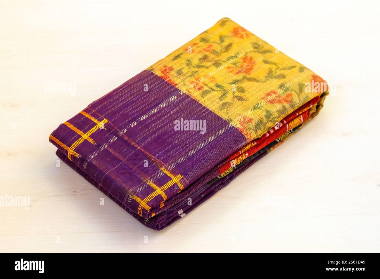 Un sari di cotone piegato è esposto su uno sfondo di legno chiaro. I sari sono una scelta popolare per le donne del Bangladesh, indossati durante festival, matrimoni, e. Foto Stock