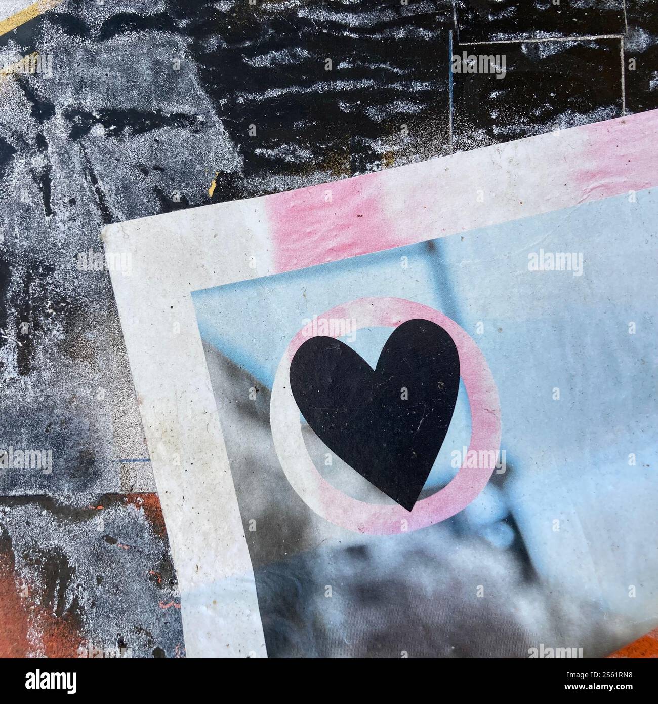 Primo piano di un pezzo artistico con un cuore nero all'interno di una forma circolare, su uno sfondo grunge testurizzato con colori contrastanti. Foto Stock