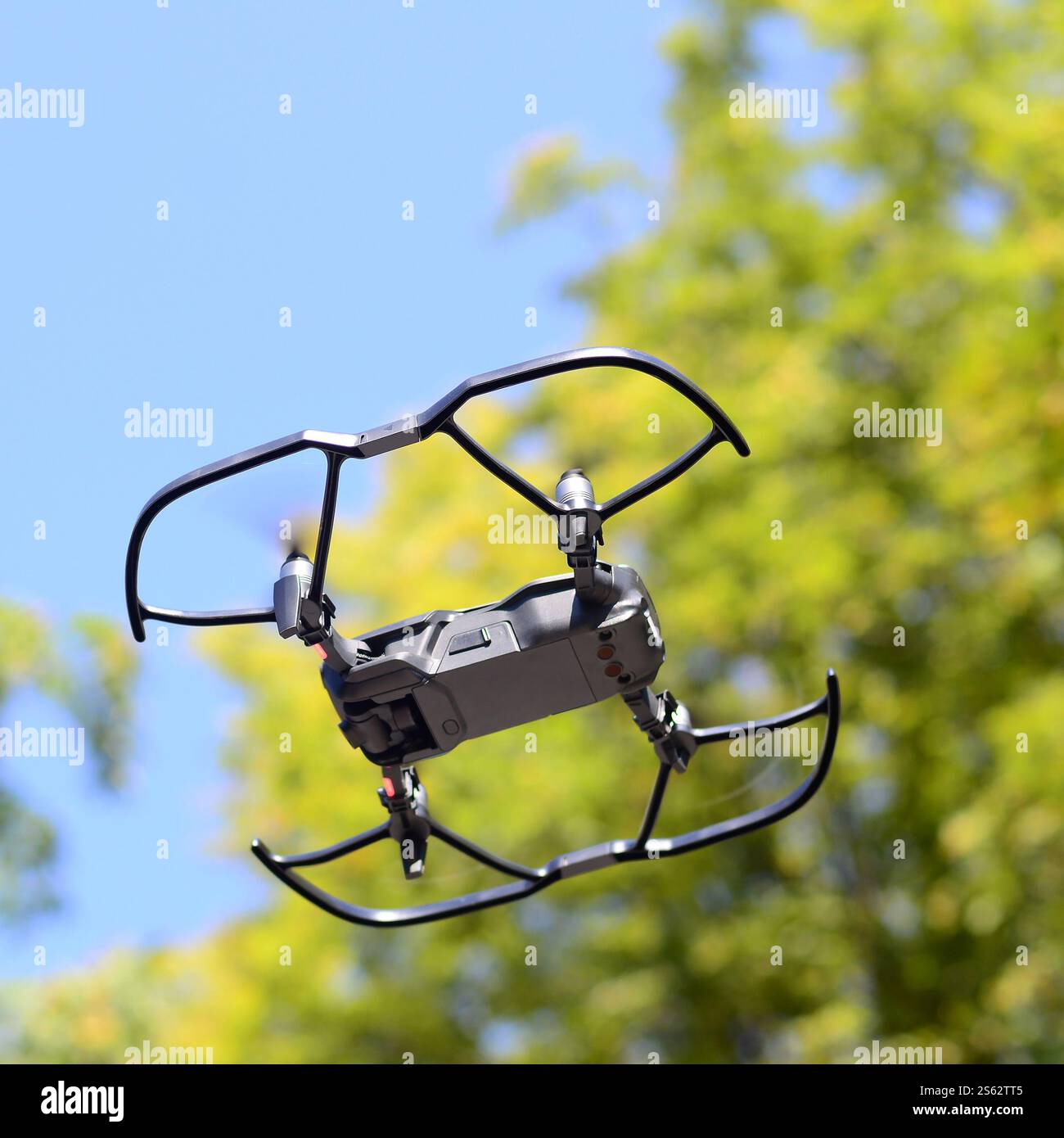 Drone con fotocamera decolla dalla terraferma e vola per scattare foto aeree al tramonto davanti agli alberi. Drone con fotocamera decollo da Foto Stock