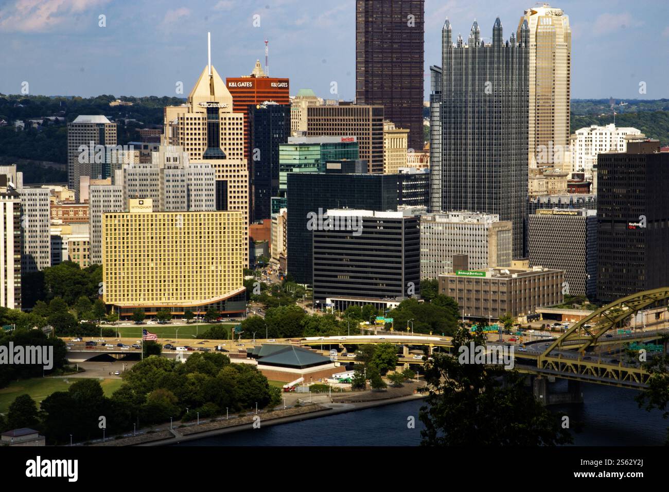 Pittsburgh, Pennsylvania, Stati Uniti - 8 agosto 2023: Edifici alti riflettono la luce del sole lungo il fiume con lussureggianti parchi verdi sottostanti, creando una vivace città a. Foto Stock