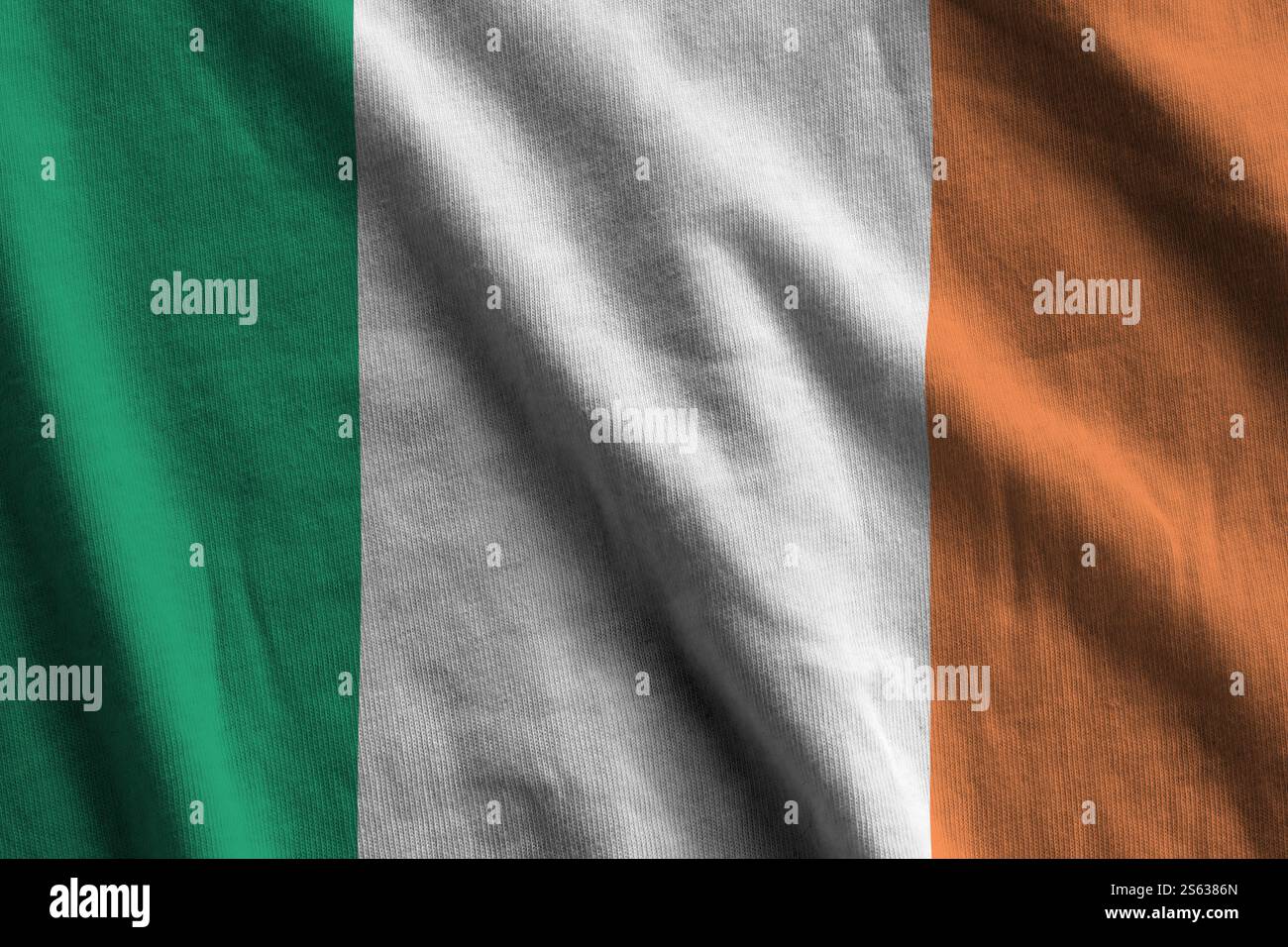 Bandiera dell'Irlanda con grandi pieghe che sventolano da vicino sotto la luce dello studio al chiuso. I simboli e i colori ufficiali dello striscione in tessuto. Bandiera dell'Irlanda con grande Foto Stock