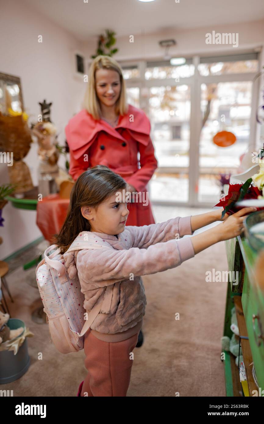 Una bambina esplora un negozio pieno di fiori colorati e decorazioni in un pomeriggio di sole Foto Stock