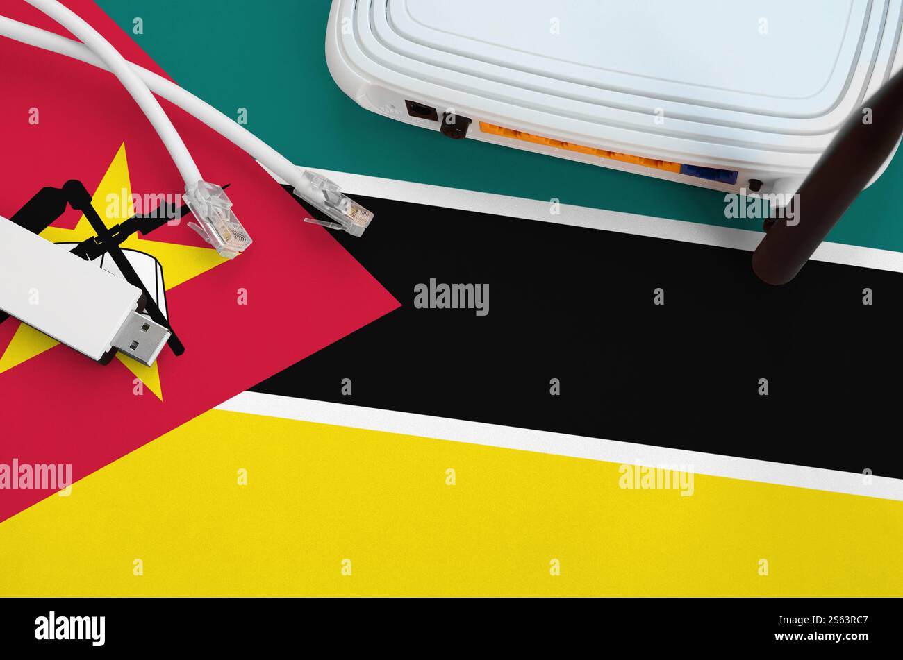 Bandiera del Mozambico raffigurata sul tavolo con cavo Internet rj45, adattatore wireless usb wi-fi e router. Concetto di connessione a Internet. Bandiera del Mozambico Foto Stock