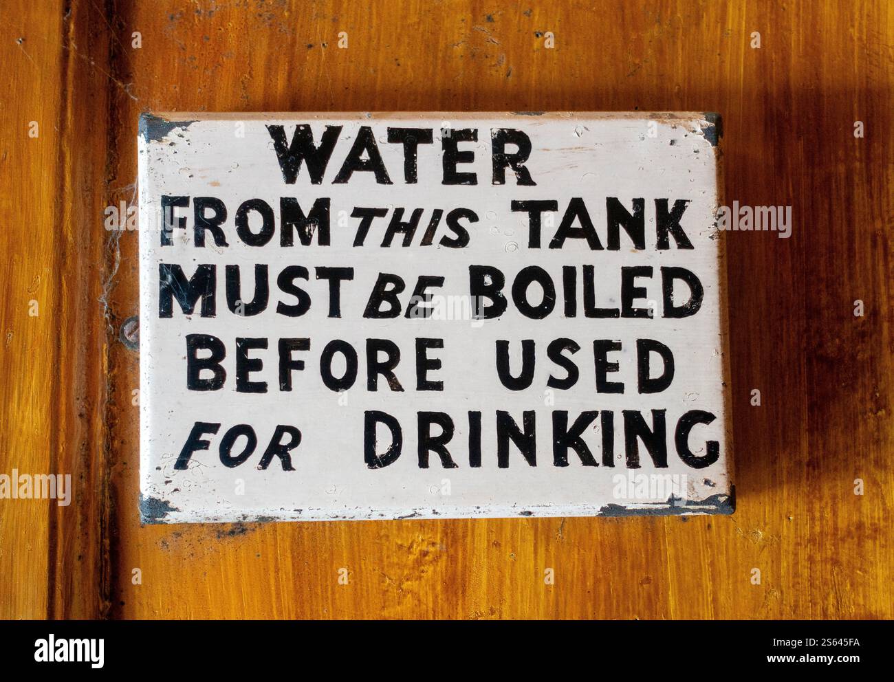 Un cartello di avvertimento in un edificio che indica di bollire l'acqua dal serbatoio prima dell'uso per bere Foto Stock