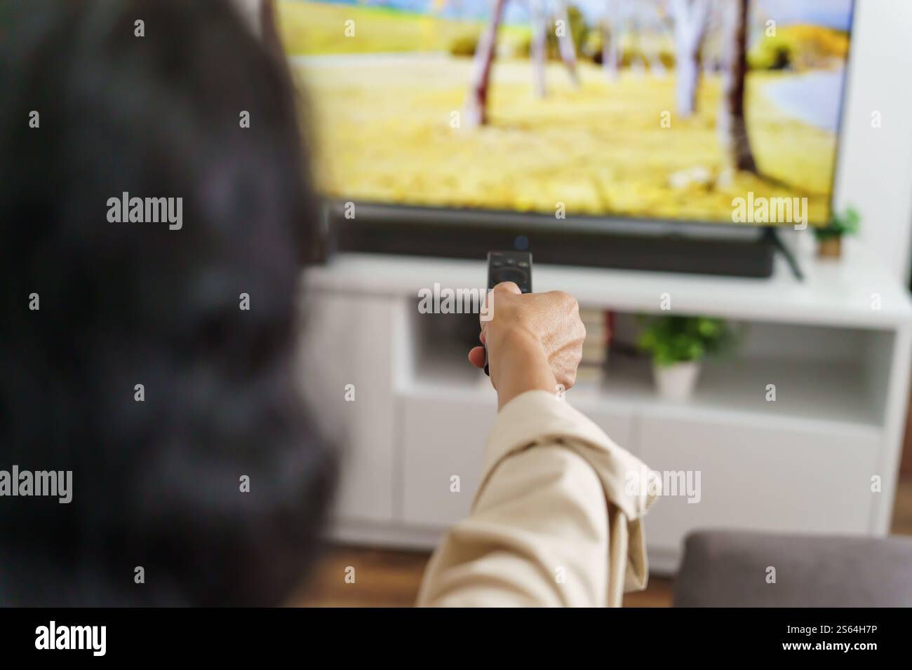 Donna anziana che guarda la smart TV e usa il telecomando che tiene la mano la televisione telecomando audio la donna asiatica di mezza età la televisione di film Foto Stock