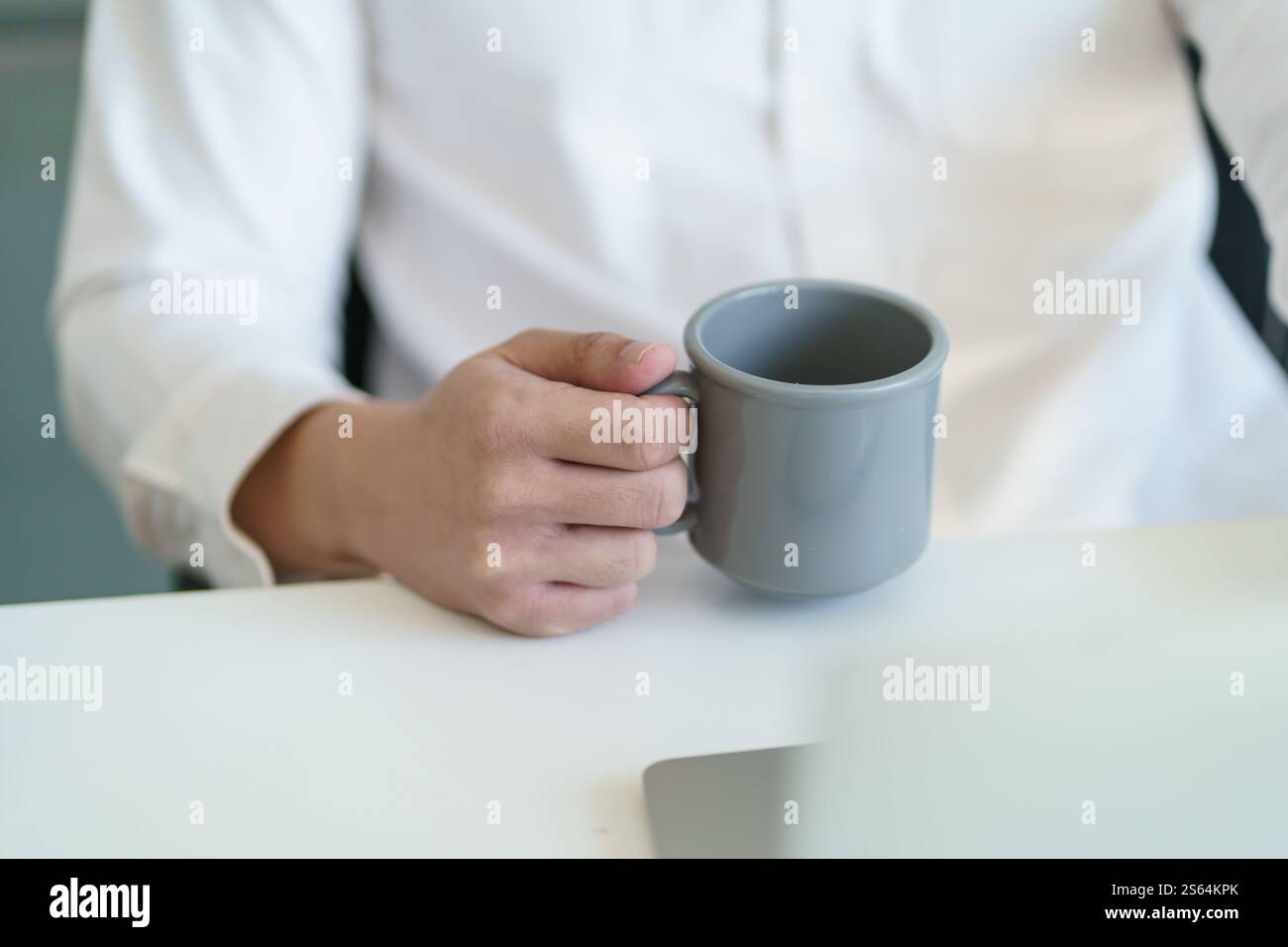 Felice giovane uomo d'affari. bere un caffè e lavorare al computer portatile mentre si è seduti in ufficio. Foto Stock