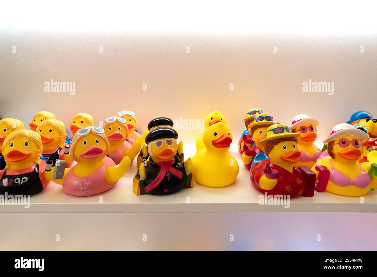 Varie anatre giocattolo di gomma gialle su uno scaffale in un negozio che vende come regalo Foto Stock