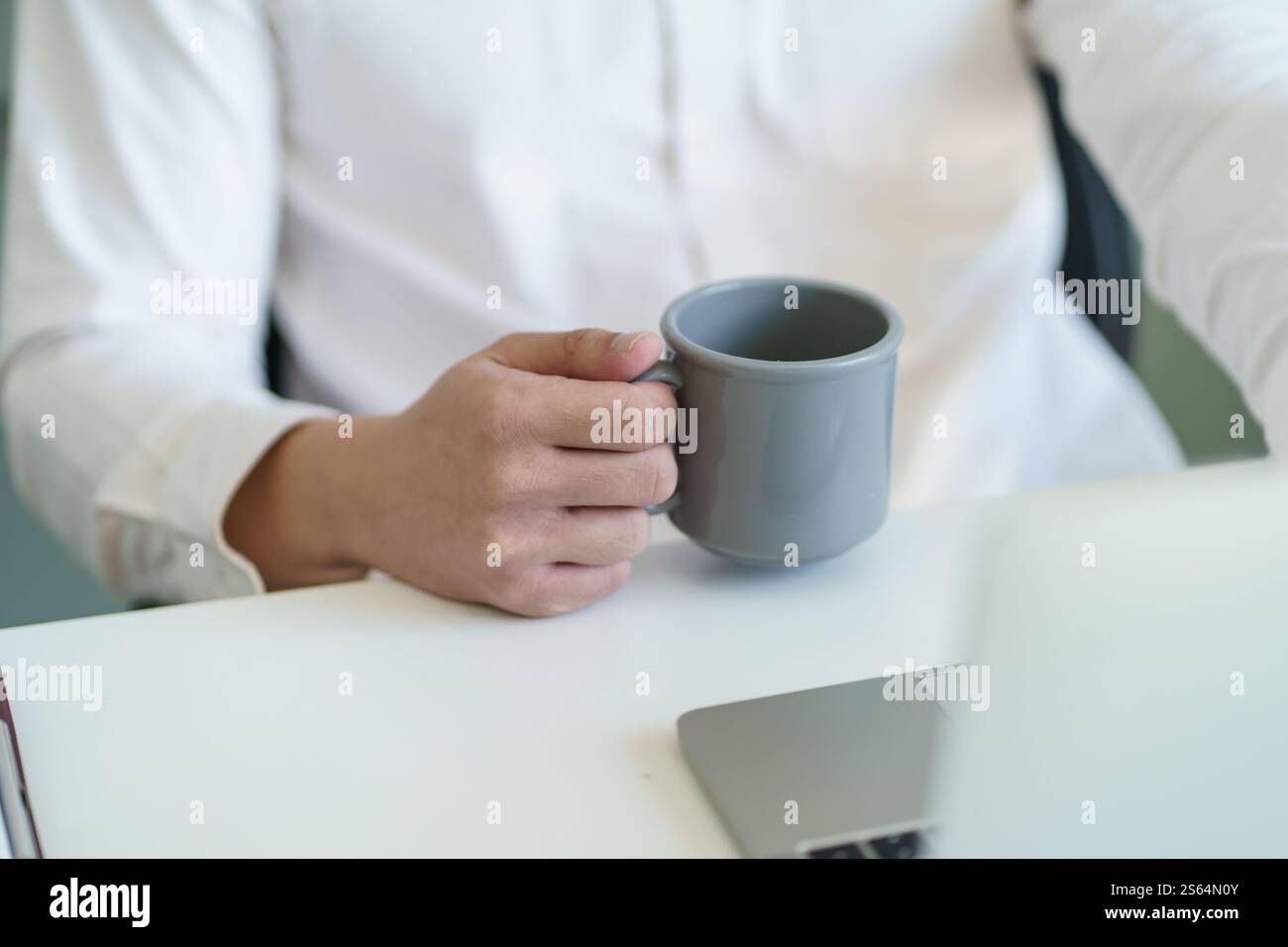 Felice giovane uomo d'affari. bere un caffè e lavorare al computer portatile mentre si è seduti in ufficio. Foto Stock