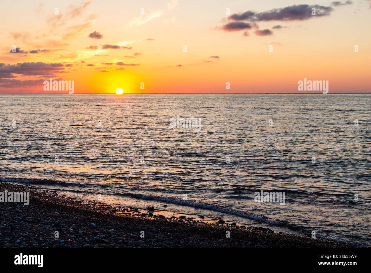 Viaggio in Georgia - vista dell'acqua del Mar Nero e tramonto dal sole dalla spiaggia di ciottoli di Batumi la sera d'autunno Foto Stock