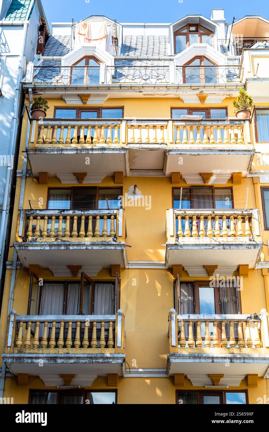 Viaggia in Georgia - facciata del vecchio edificio giallo di appartamenti nella città di Batumi nel soleggiato giorno d'autunno Foto Stock