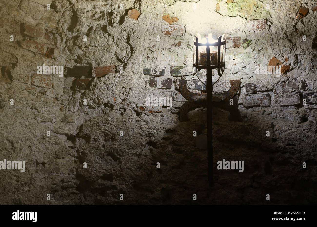Torcia del castello medievale illuminata appesa su un muro di pietra, oggetti d'epoca e sfondo. Torcia medievale illuminata appesa su un muro di pietra, vintage Foto Stock