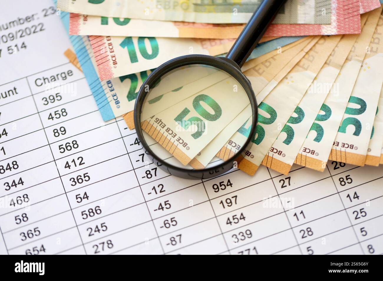 Concetto di business e risparmio con molte banconote in euro e lente d'ingrandimento in primo piano. Concetto di business e risparmio con molte bollette in euro e. Foto Stock