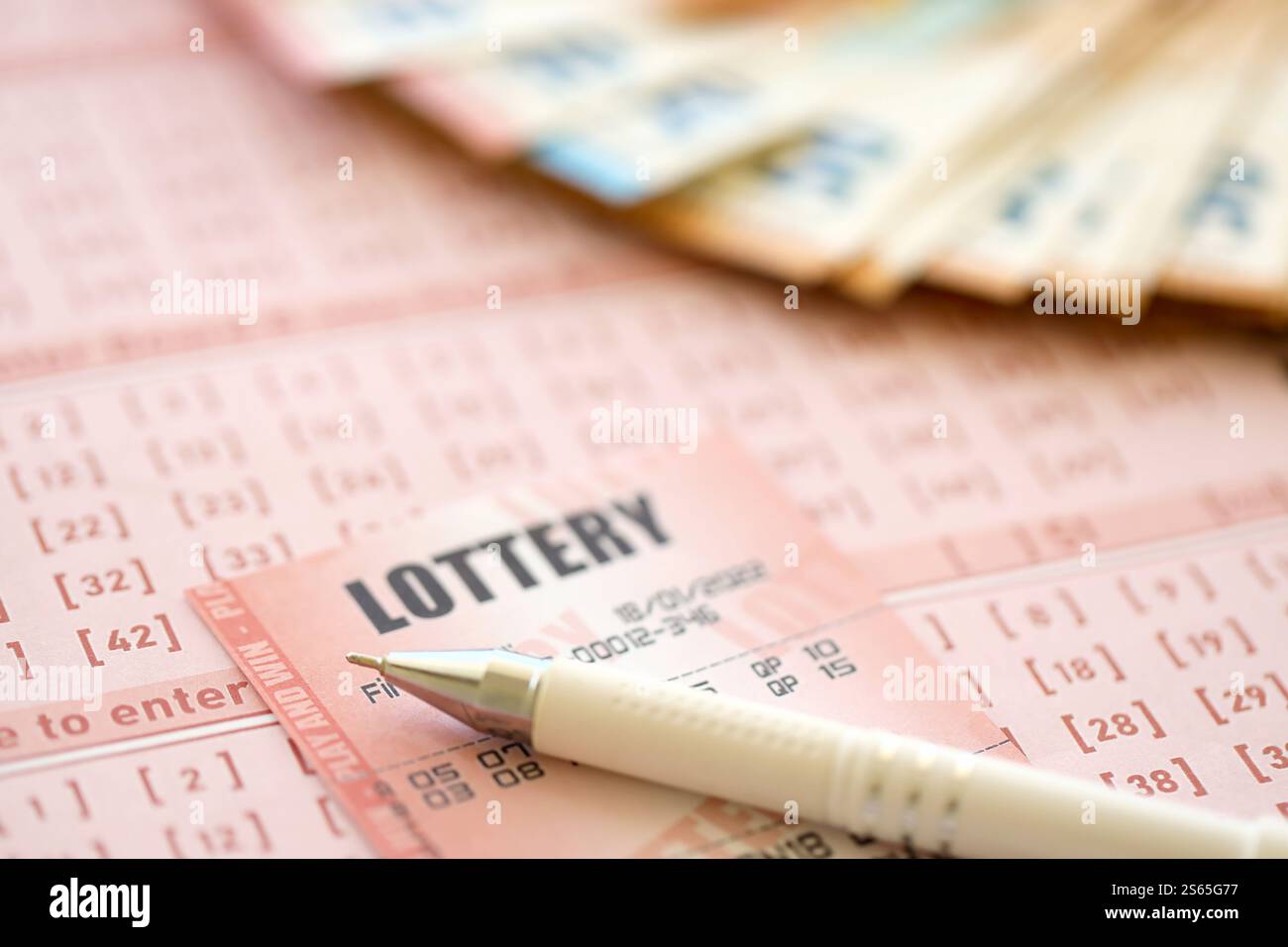 Biglietto della lotteria e ricevuta del gioco d'azzardo sul tavolo con penna e banconote in euro dell'Unione europea da vicino. Biglietto della lotteria e ricevuta del gioco d'azzardo sul tavolo con Foto Stock