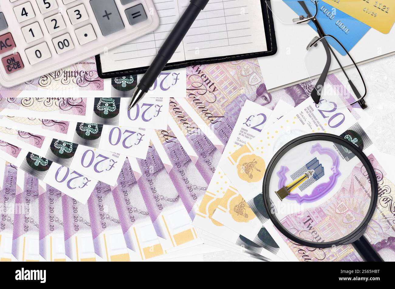 Banconote da 20 sterline britanniche e calcolatrice con occhiali e penna. Concetto di stagione del pagamento delle imposte o soluzioni di investimento. Alla ricerca di un lavoro con stipendio elevato Foto Stock