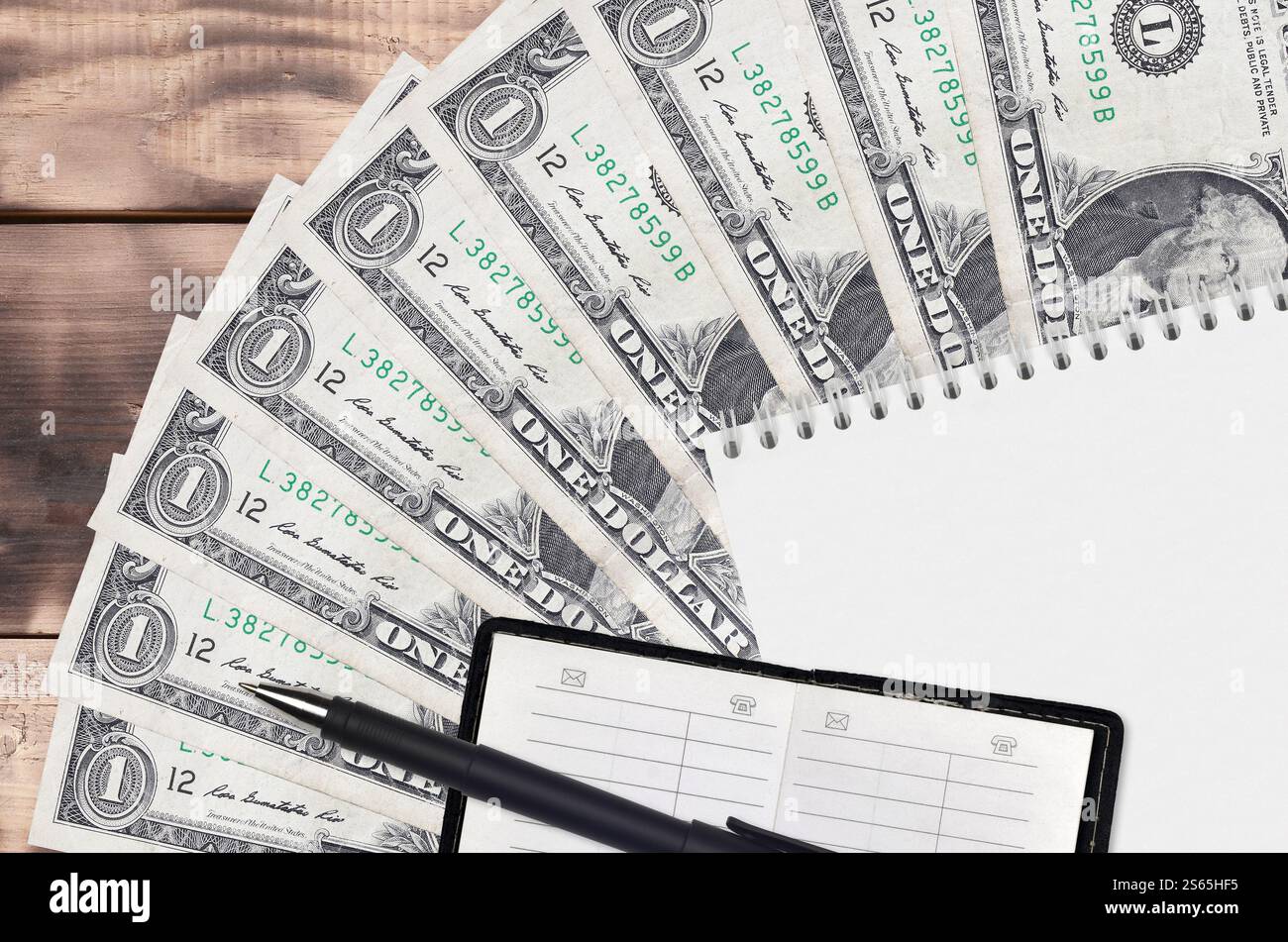 1 dollaro USA di banconote, ventola e blocco note con rubrica e penna nera. Concetto di pianificazione finanziaria e strategia aziendale. Contabilità e investimenti. 1 Foto Stock