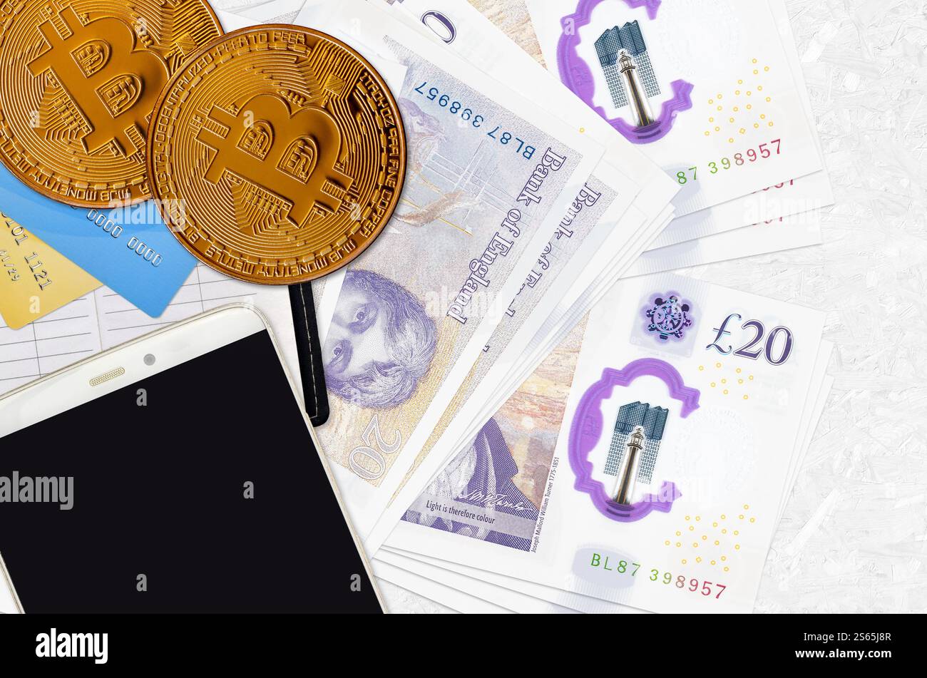 Banconote da 20 sterline britanniche e bitcoin dorati con smartphone e carte di credito. Concetto di investimento in criptovaluta. Crypto mining o trading Foto Stock