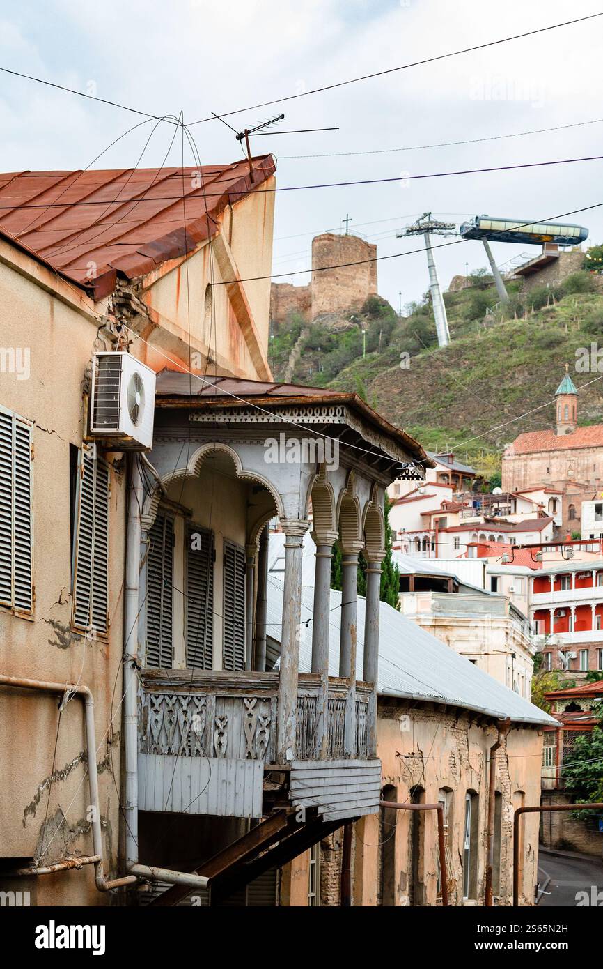 Viaggia verso la Georgia, una casa malandata con balcone in legno intagliato nella vecchia città di Tbilisi in un giorno nuvoloso d'autunno Foto Stock
