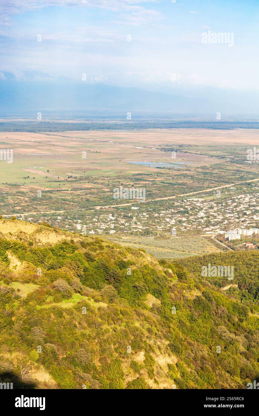 Viaggia verso la Georgia - pendio montano ricoperto di vegetazione e vista della valle di Alazan nella regione di Kakheti dalla città di Signagi in Georgia in un giorno d'autunno soleggiato Foto Stock