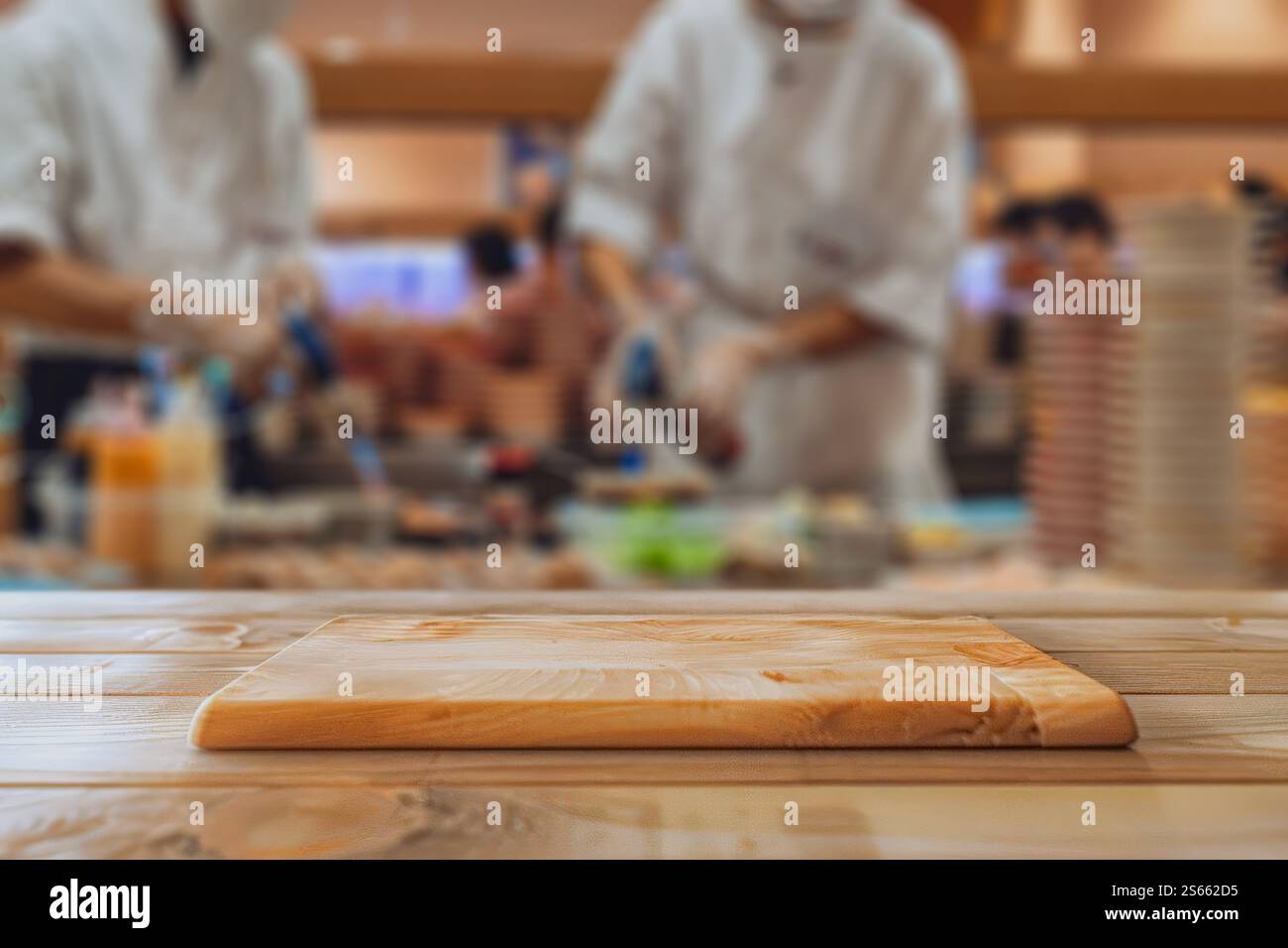 Tavolo in legno con piedistallo in blur Sushi Chef professionisti che preparano piatti freschi in una cucina del ristorante Foto Stock