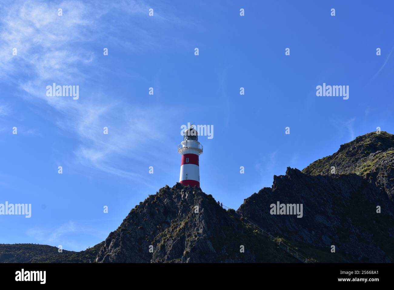 Un faro maestoso che si erge alto e guida le navi attraverso i mari turbolenti. Situato a Cape Palliser, Wairarapa, nuova Zelanda Foto Stock