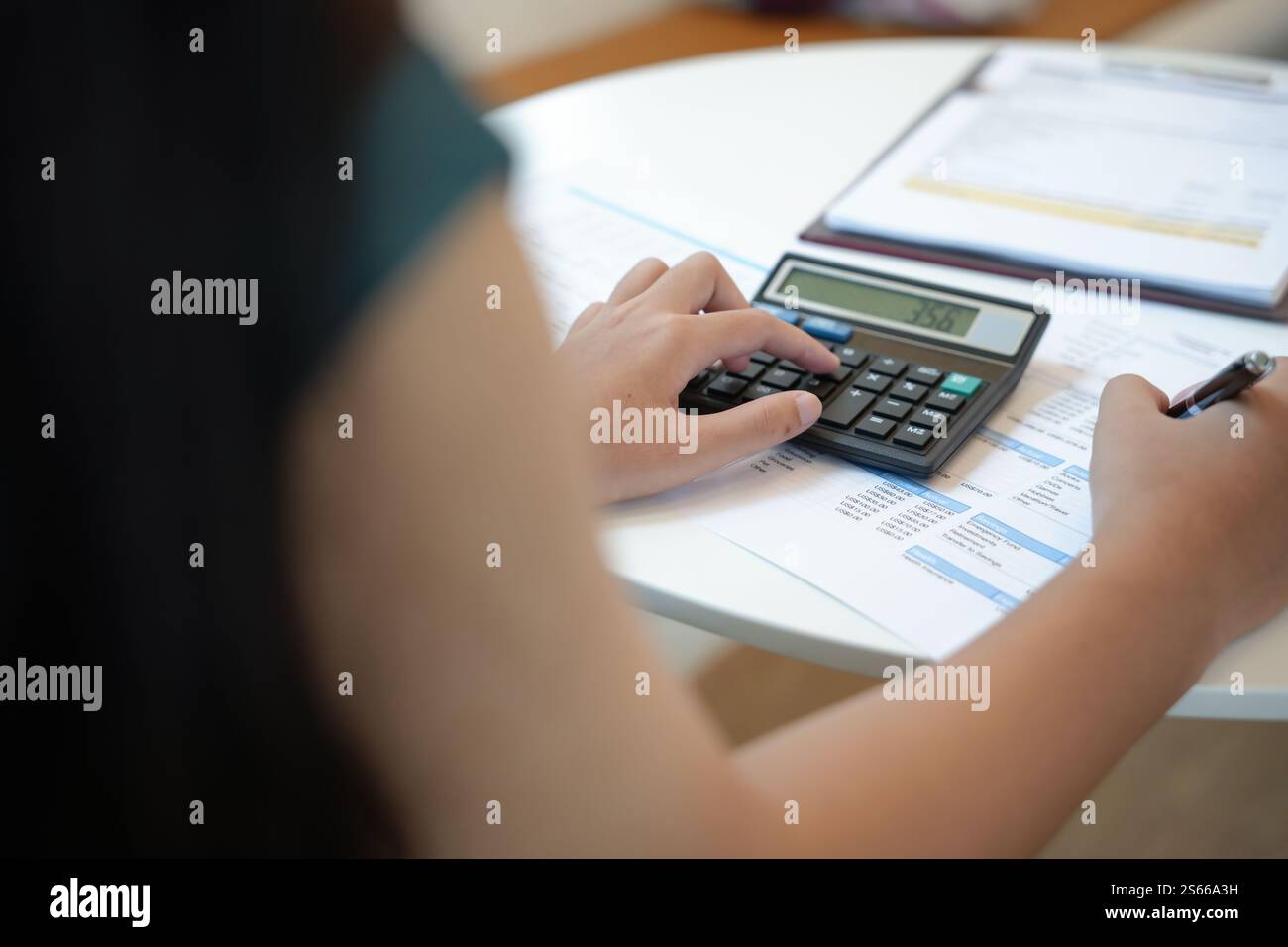 Imprenditrice contabile che analizza i grafici di investimento fattura e preme i pulsanti di calcolo sui documenti. Contabile contabile impiegato consulente bancario Foto Stock