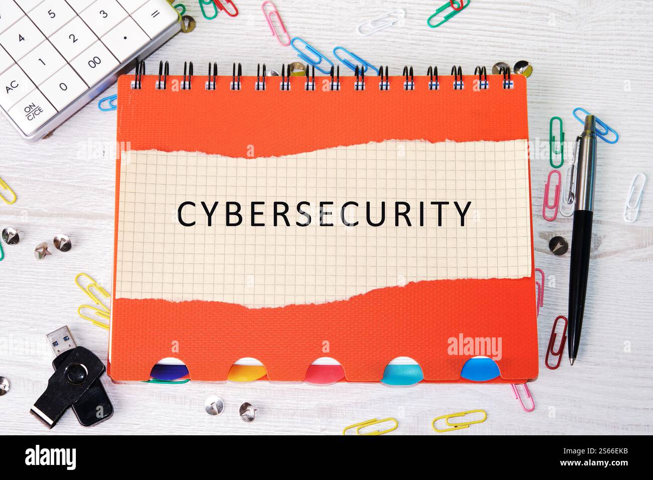 Un notebook con etichetta cybersecurity è collocato su una scrivania circondata da materiali per ufficio. Foto Stock