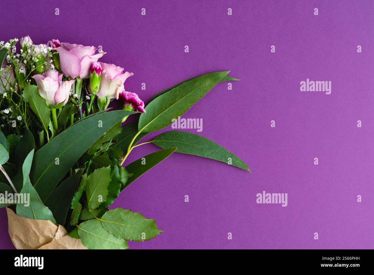 Bouquet di fiori con rifilatura a nastro e rose viola con eucalipto su sfondo viola. Spazio copia. Vista dall'alto. Foto Stock
