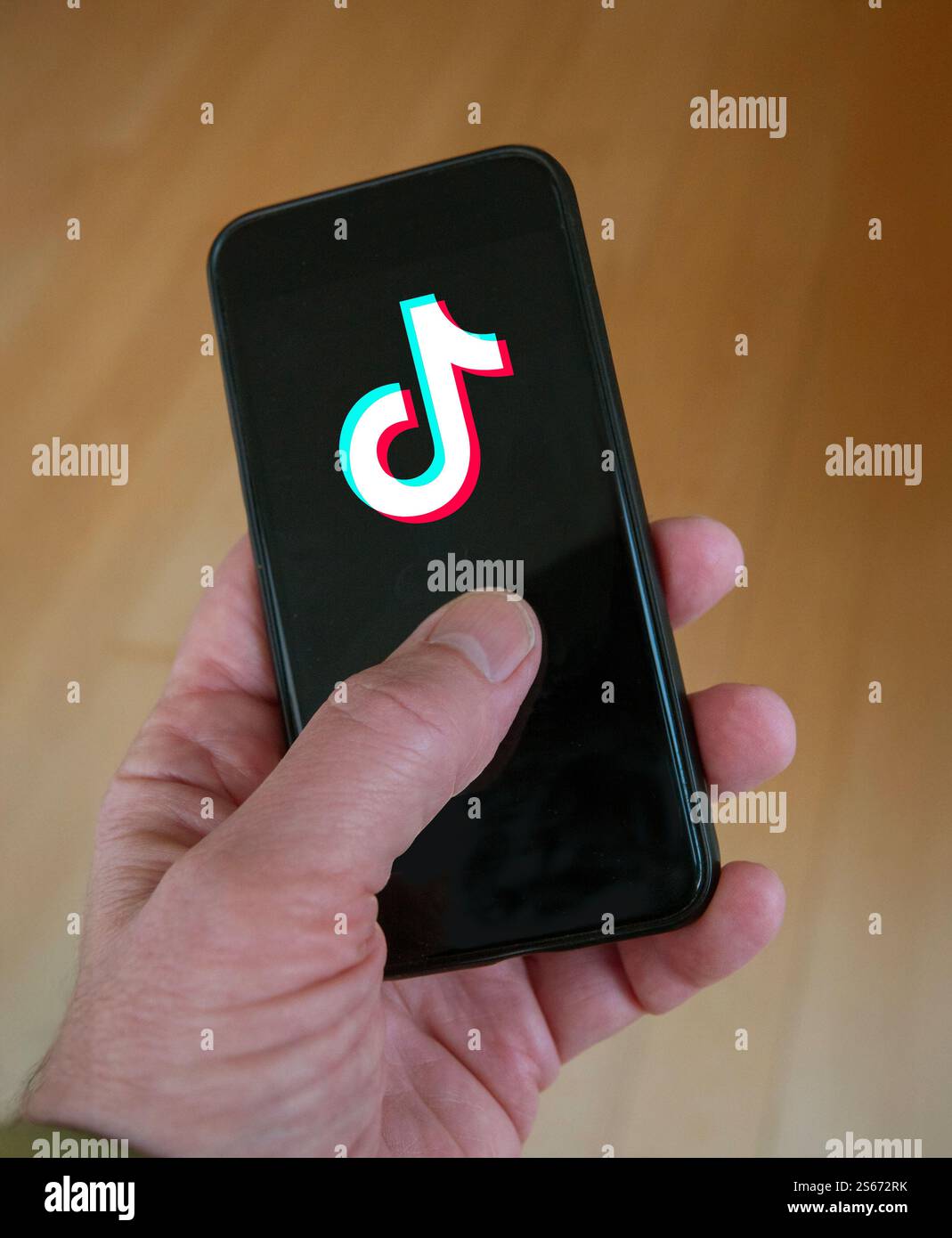 Logo TikTok sullo schermo dello smartphone su sfondo nero tenuto in mano. TikTok è una popolare app di social networking di proprietà di ByteDance. Foto Stock