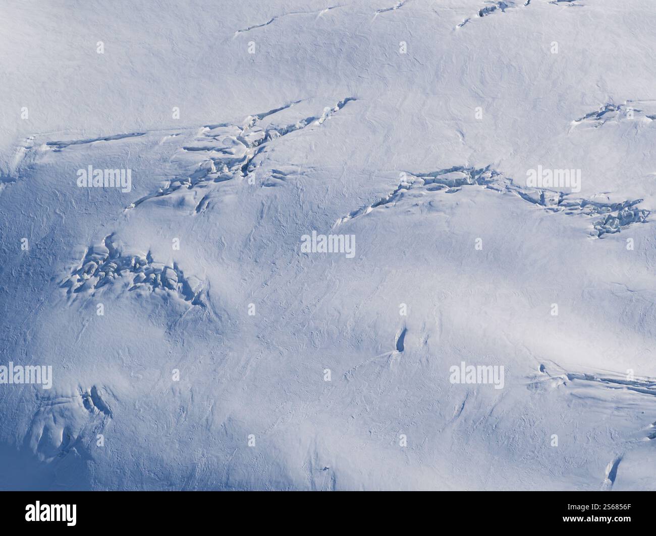 Una vista aerea delle intricate formazioni di neve delle Alpi francesi. Il vento ha scolpito la neve in uno schema ipnotico. Foto Stock