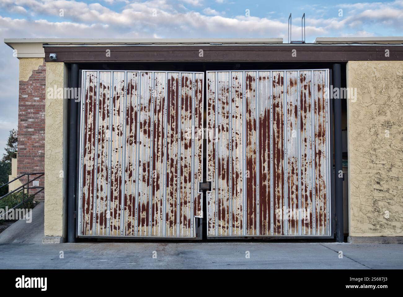 I cancelli antiruggine sul recinto del cassonetto chiudono l'esterno dell'edificio commerciale. Foto Stock