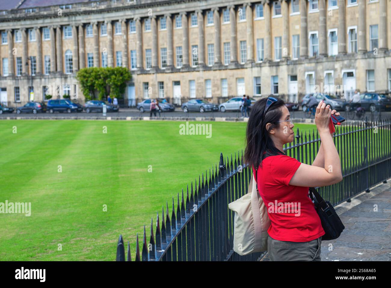 Una turista viene fotografata mentre scatta una fotografia dell'iconica Royal Crescent a Bath, Inghilterra, Somerset, Regno Unito Foto Stock