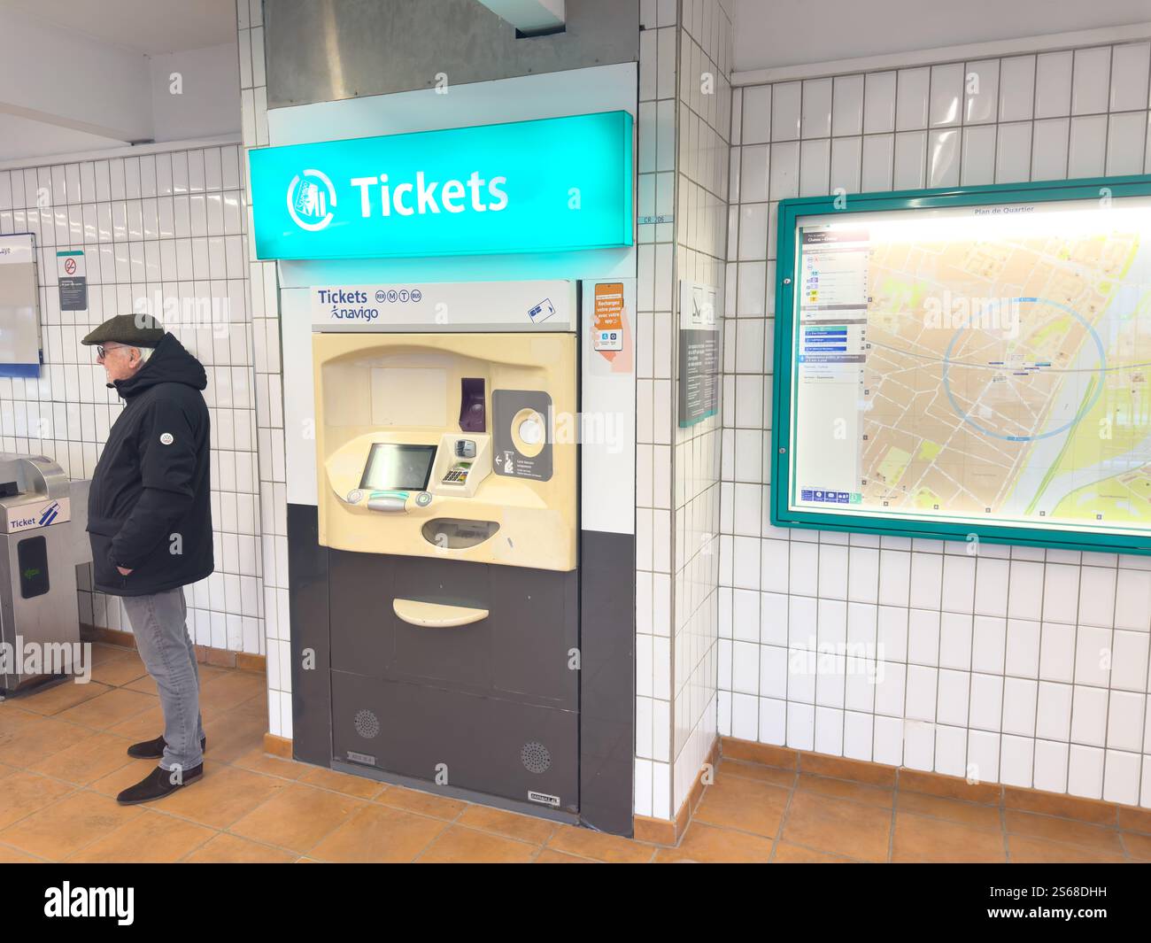 Distributore automatico di biglietti situato in una stazione ferroviaria con un passeggero in attesa nelle vicinanze Foto Stock