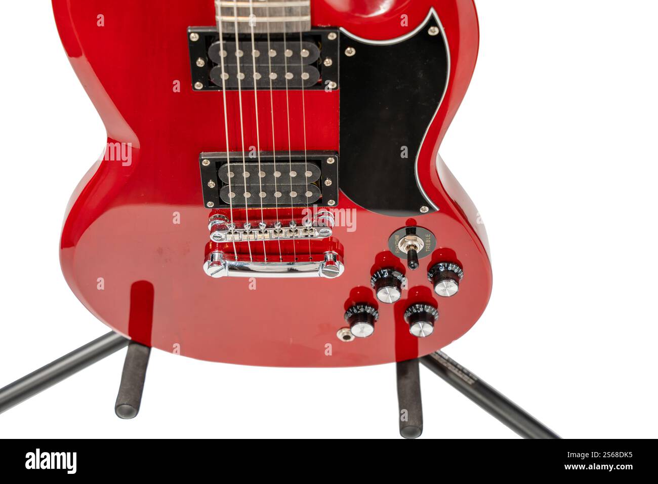 Una chitarra elettrica rossa con un ponte nero e un picchetto nero. La chitarra è su uno stand ed è al centro dell'attenzione Foto Stock