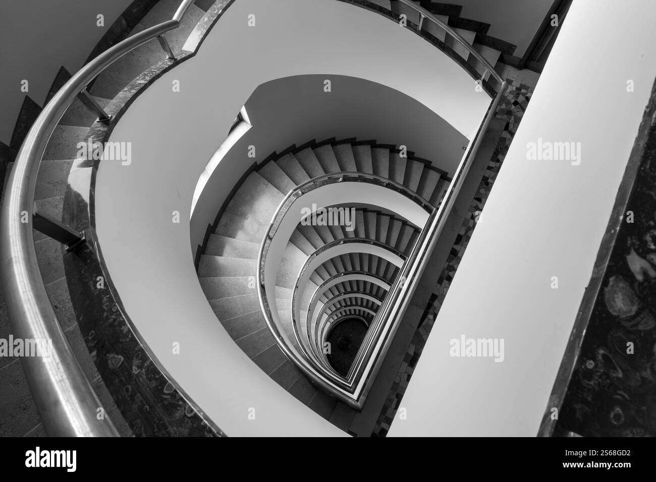 Immagine in bianco e nero che cattura l'intricata scala a chiocciola dall'alto con curve eleganti. Foto Stock