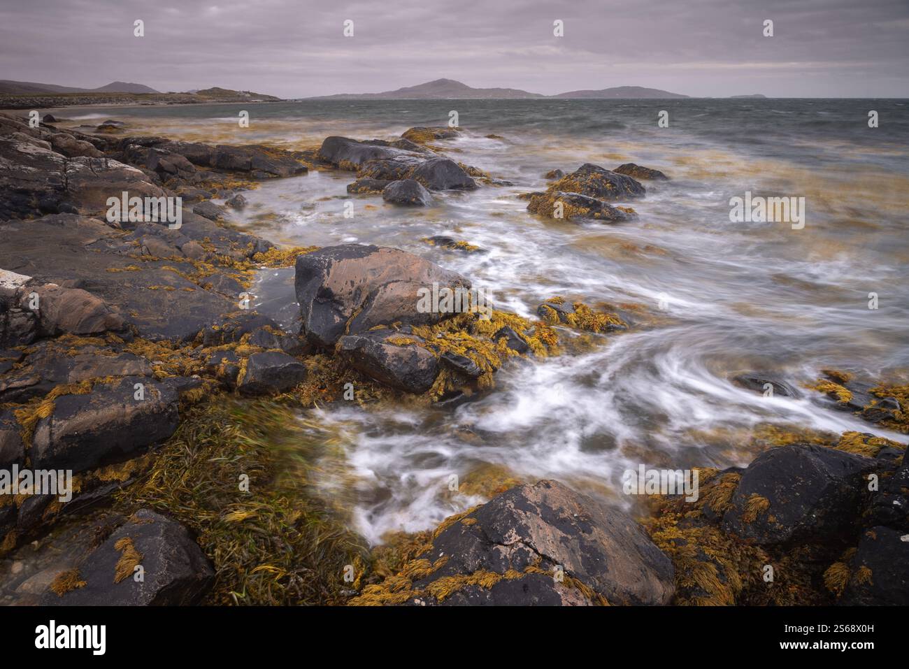 Alghe che girano tra le onde di una marea in arrivo sulla spiaggia di Kilbride sulla costa di Uist, Ebridi esterne, in una giornata nuvolosa e ricoperta di nuvole. Foto Stock