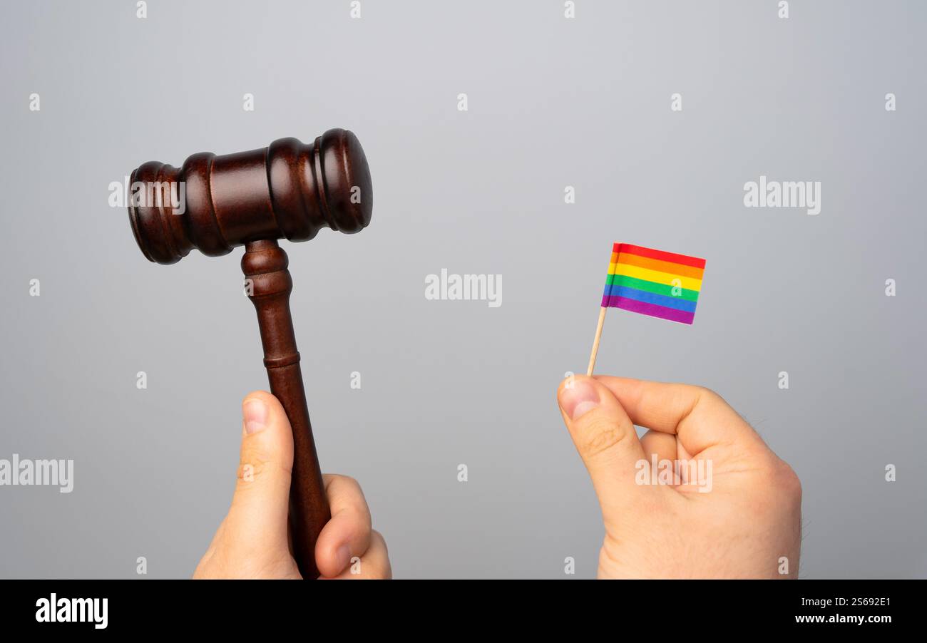 Bandiera LGBT e martello del giudice in mano. Concetto di decisioni legislative e adozione della legge sulla protezione dei diritti della comunità LGBT. Restrizione Foto Stock