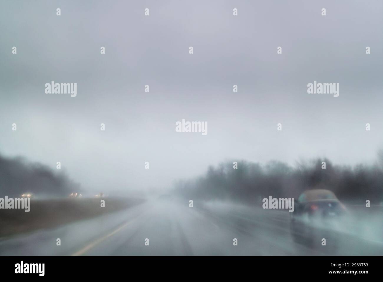 Auto che guidano in condizioni meteorologiche avverse, con nebbia e pioggia battente in autostrada, sfocatura del movimento all'interno della telecamera a lunga esposizione Foto Stock