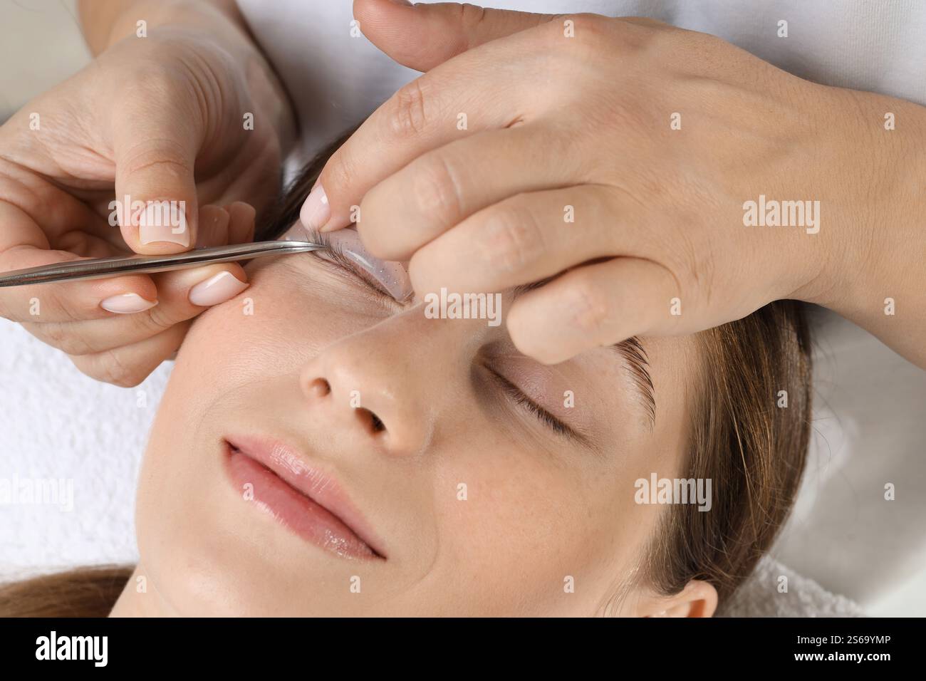 Procedura di laminazione delle ciglia. Estetista che posiziona il cuscinetto in silicone sulla palpebra della donna nel salone di bellezza, primo piano Foto Stock