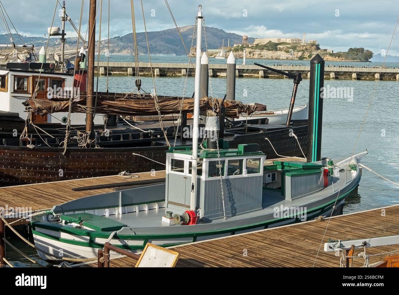 Antiche barche da pesca in legno con vista remota dell'isola di Alcatraz presso il San Francisco Maritime National Historical Park Foto Stock