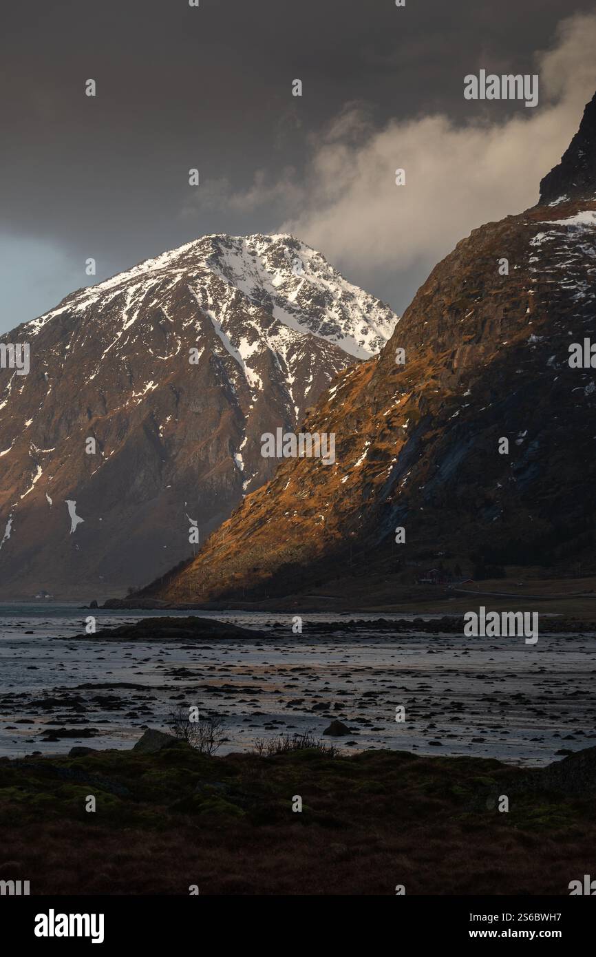 Montagne innevate a Lofoten, Norvegia, immerse nella luce dorata delle ore. Una scena serena e mozzafiato, ideale per la fotografia di paesaggi. Foto Stock