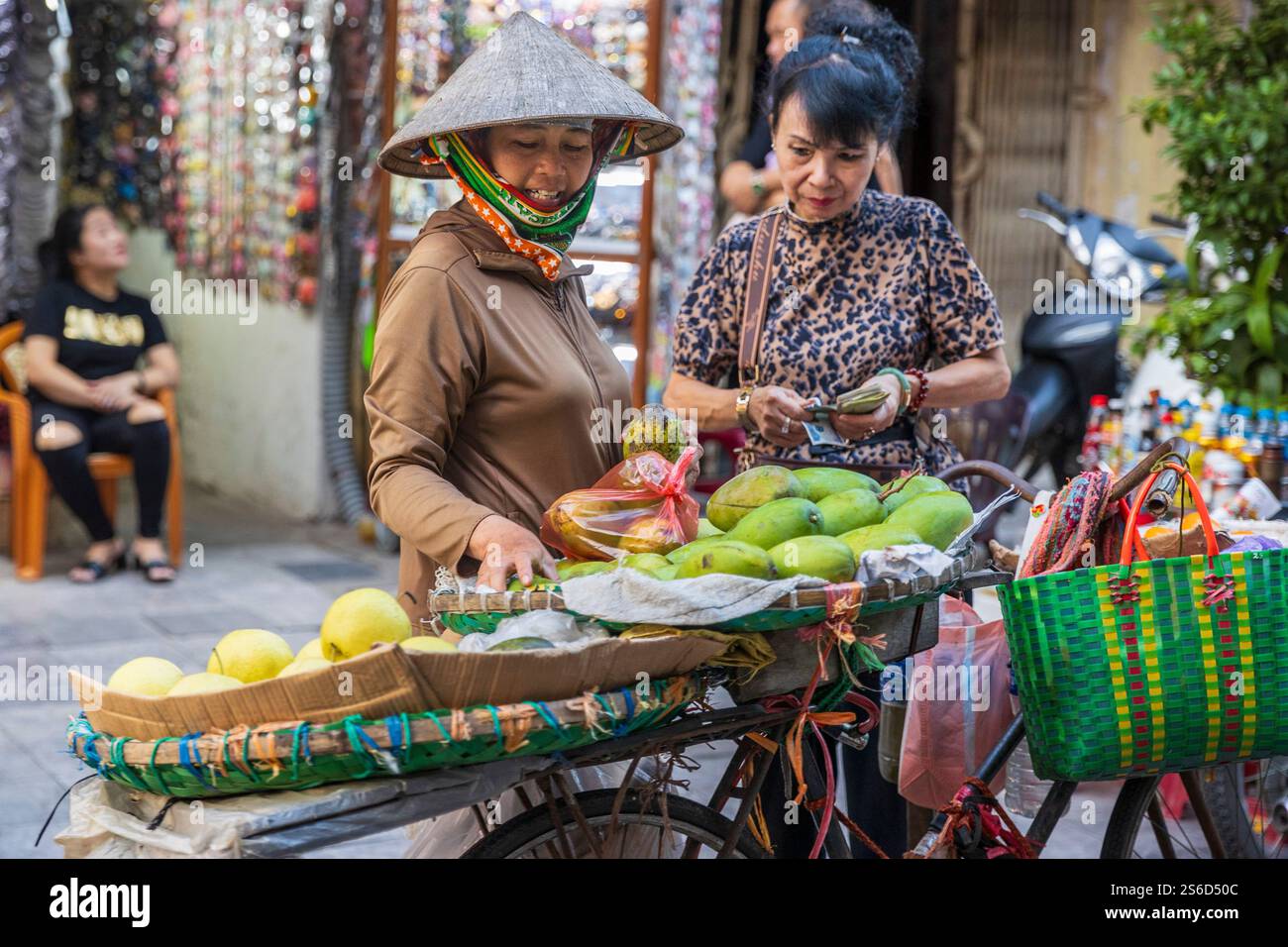 Cliente che acquista frutta in uno stallo di Hanoi, Vietnam, venerdì 1 novembre 2024. Foto: David Rowland / One-Image.com Foto Stock