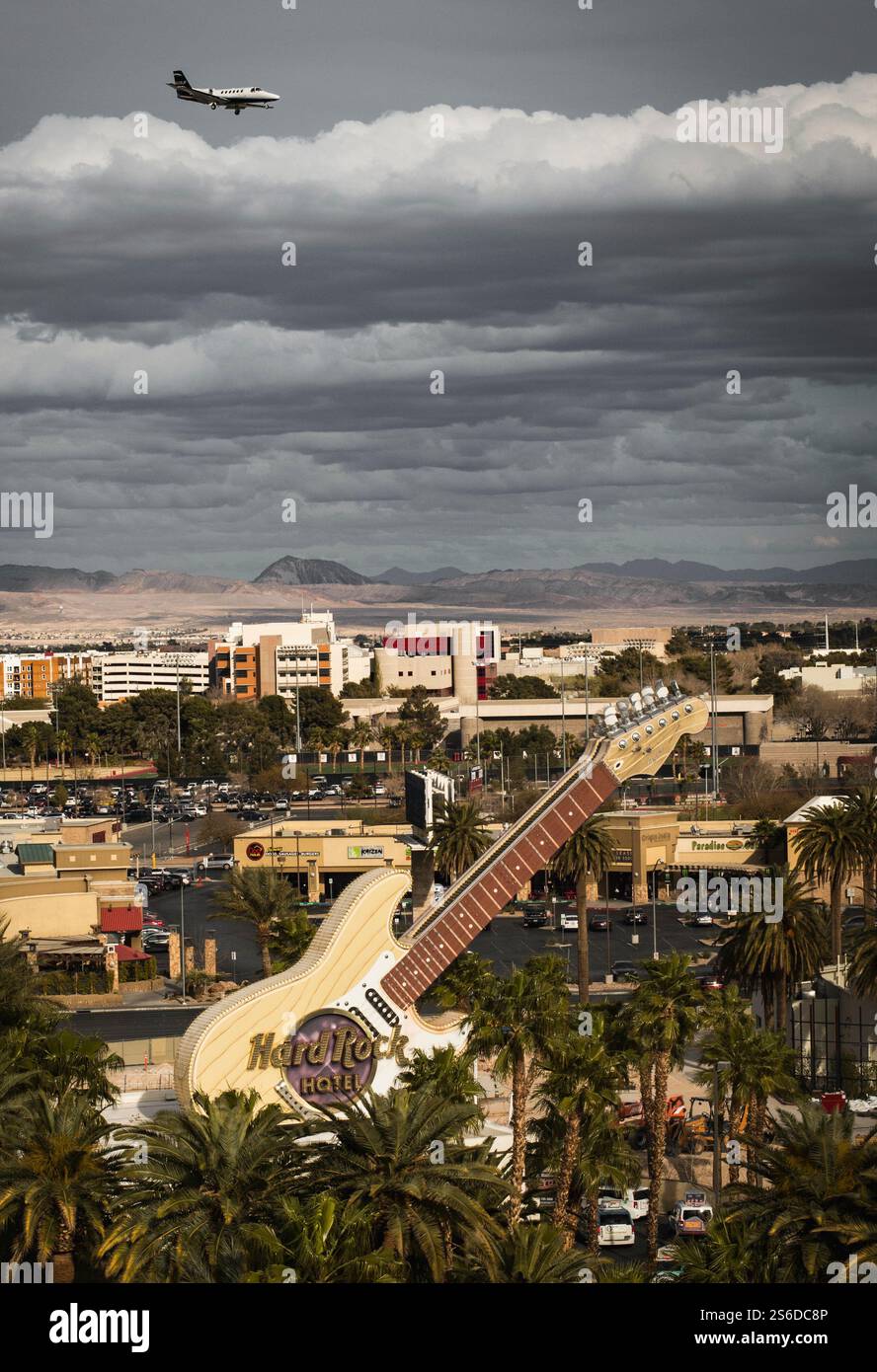 L'insegna della chitarra dell'Hard Rock Casino di Las Vegas si erge alto mentre un aereo vola attraverso nuvole spettacolari, invitando storie infinite da questa città deserta. Foto Stock