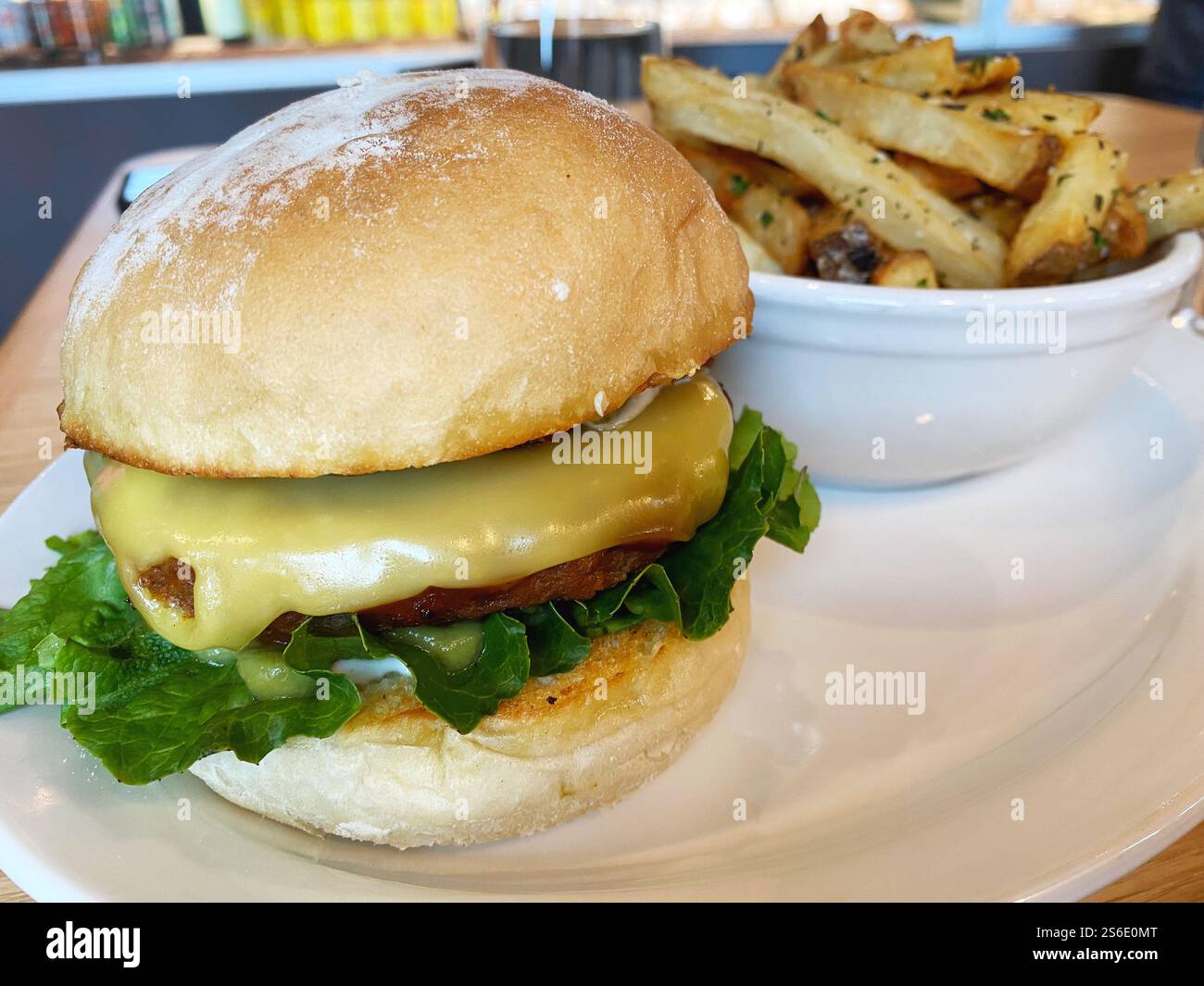 Hamburger vegano con formaggio e un contorno di patatine fritte. Foto Stock