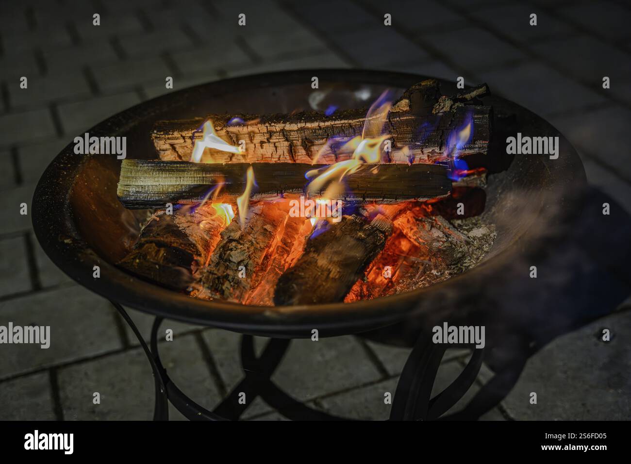 Bruciare la legna in una ciotola su ciottoli scuri, scaldare le fiamme di notte Foto Stock
