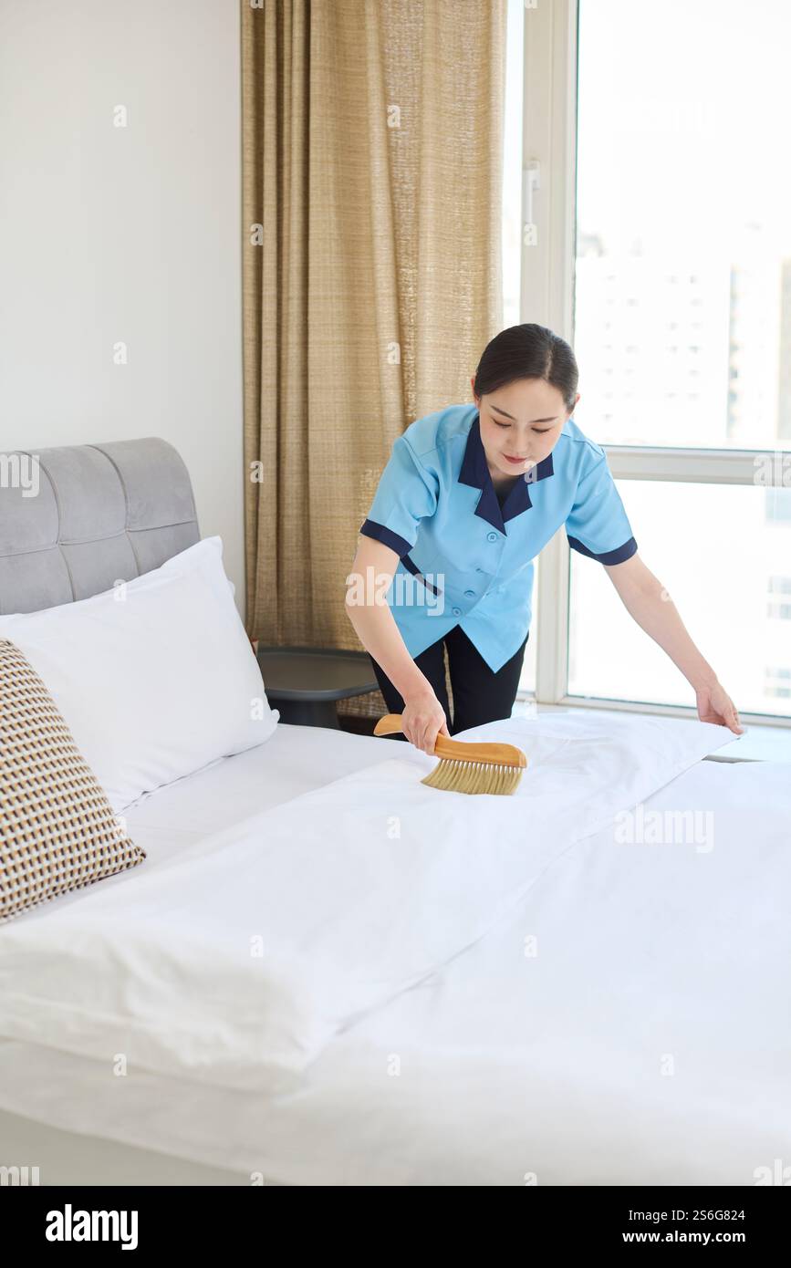 Donna che pulisce il letto Foto Stock