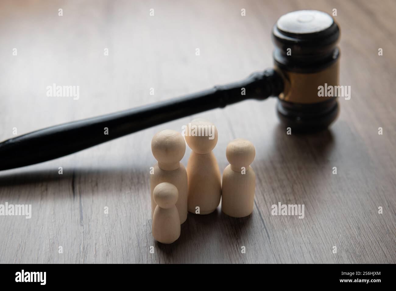Un martelletto e quattro statuette di legno che rappresentano una famiglia su un tavolo. Concetto di diritto di famiglia. Foto Stock