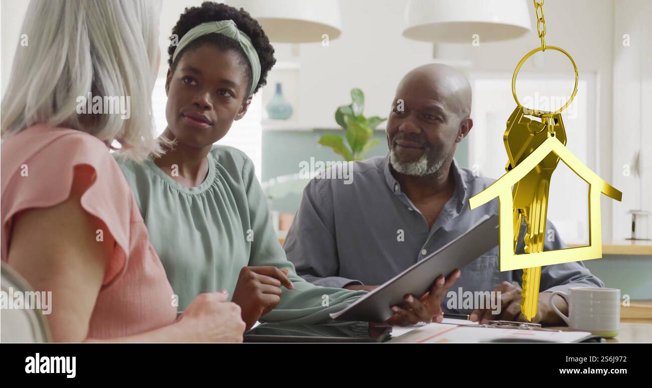 Immagine della chiave della casa d'oro su coppia diversificata con consulente finanziario donna in cucina Foto Stock