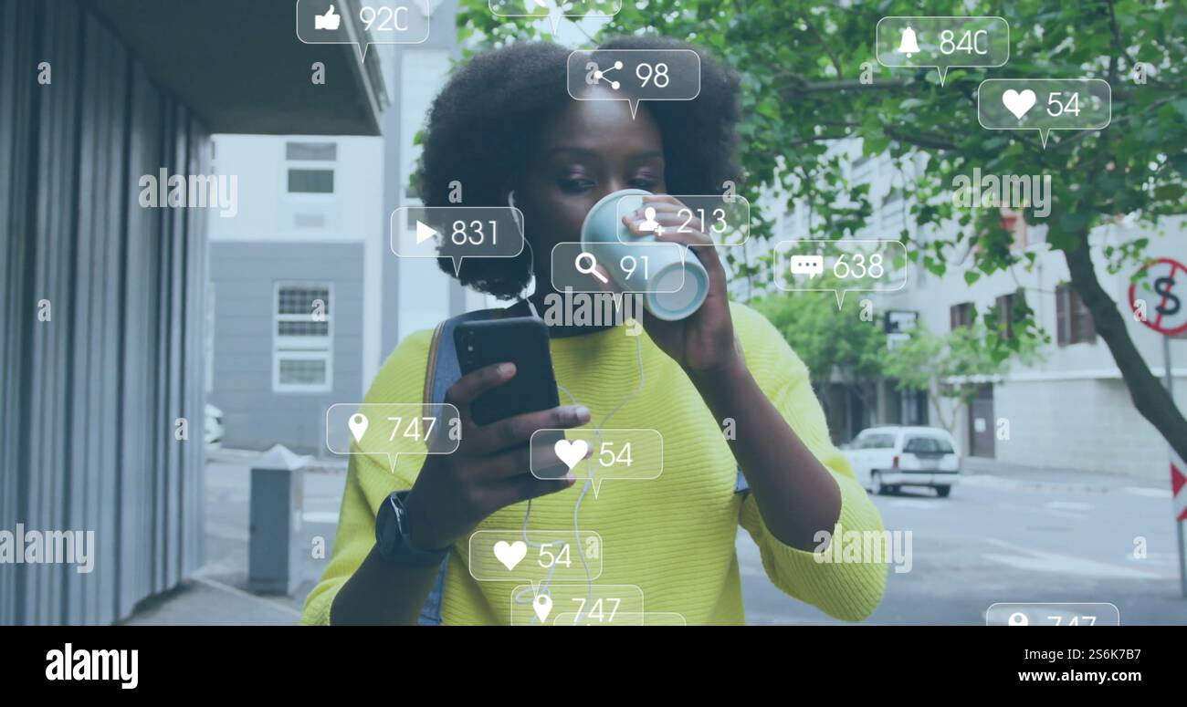 Immagine di icone dei media su una donna afroamericana che usa lo smartphone in città Foto Stock