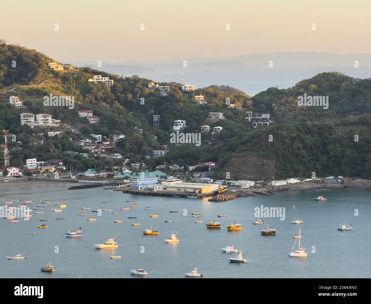 Tranquillo porto adornato da numerose barche, vicino all'incantevole cittadina di mare al tramonto, che offre paesaggi mozzafiato. Foto Stock
