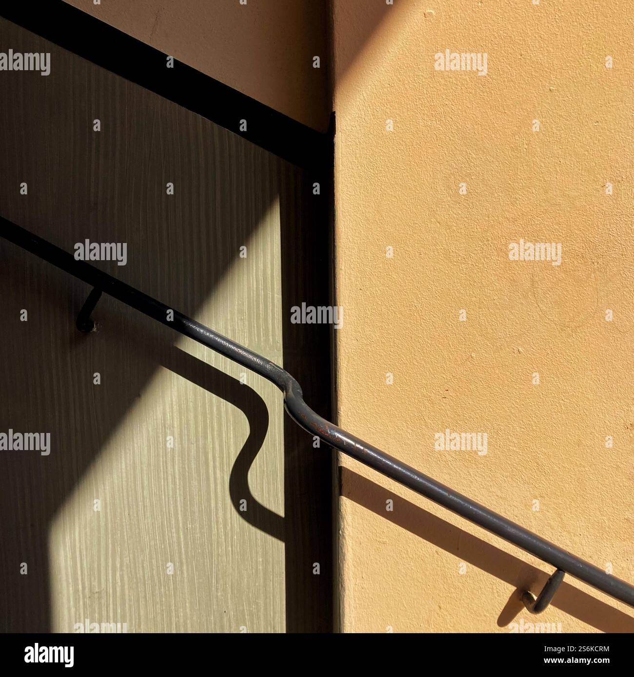 Le ombre interagiscono con un elemento architettonico minimale, sottolineando linee e texture sotto una luce naturale soffusa. - Immagine stock catturata con smartphone